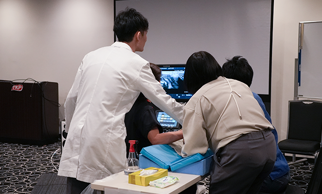 講師の石川先生が参加者と一緒にプローブを持ちつつ、レクチャーをしている写真