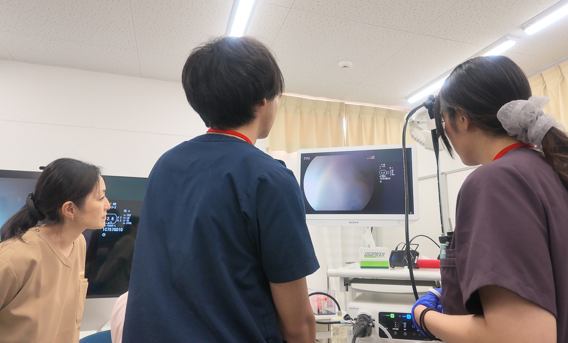 モニターを確認しながら腸生検にチャレンジする参加者と左手側から様子をうかがっている講師。