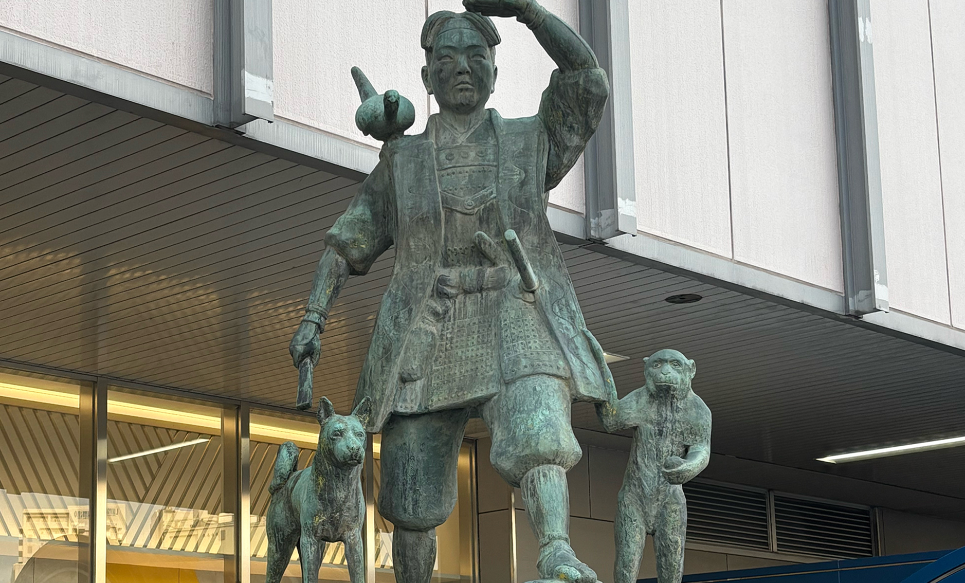 岡山駅前の桃太郎像。左手を上げて遠くを眺めているポーズをとっている。右肩に雉が止まっており、右足横に犬、左足横に猿が連れ添っている。